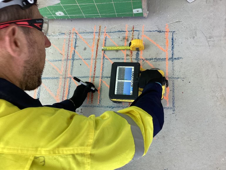 technician using a concrete scanner and marking the concrete surface